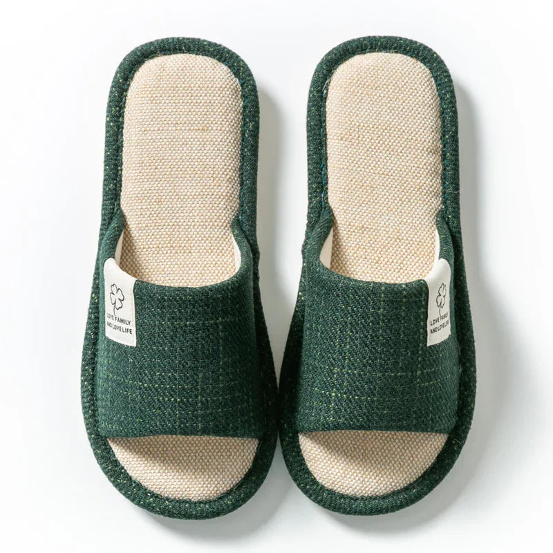 Pair of green and beige fabric open-toe indoor slippers with white tags on a white background