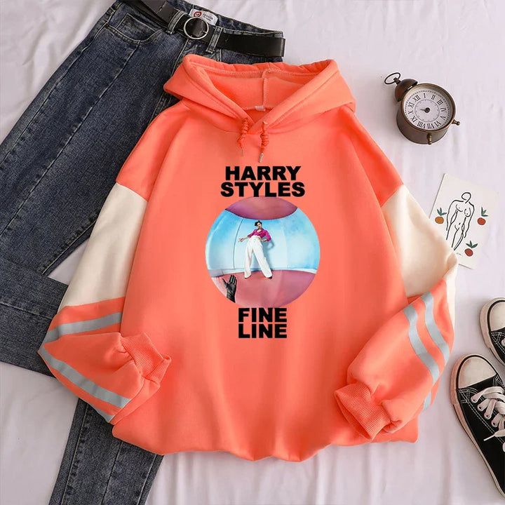 Peach Harry Styles Fine Line hoodie with white sleeves and reflective stripes, paired with black belt and jeans