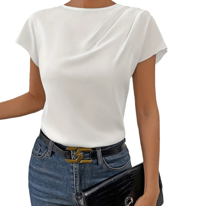 Woman wearing white short sleeve top with draped neckline, blue jeans, black belt, and holding black clutch