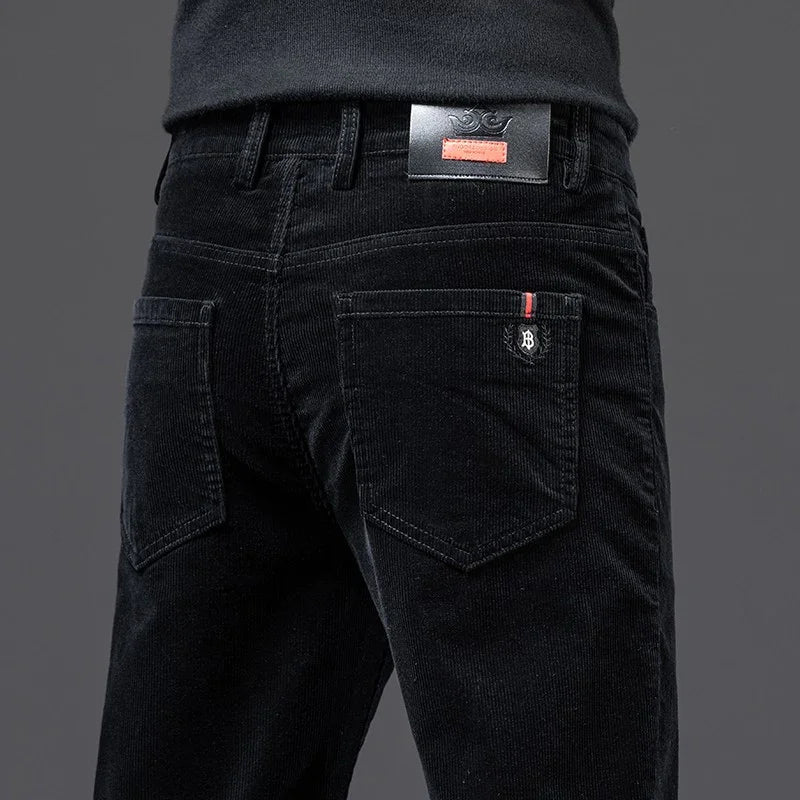 Back view of black corduroy pants with branded patch and red accent on back pocket