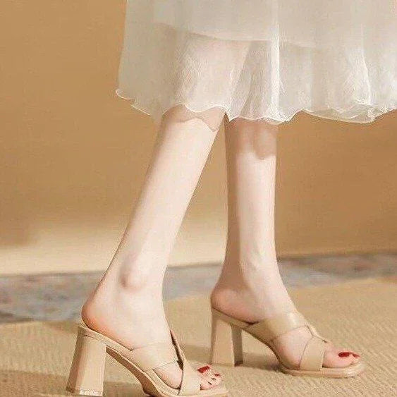 legs wearing beige high-heeled mules paired with a white sheer dress on carpeted floor
