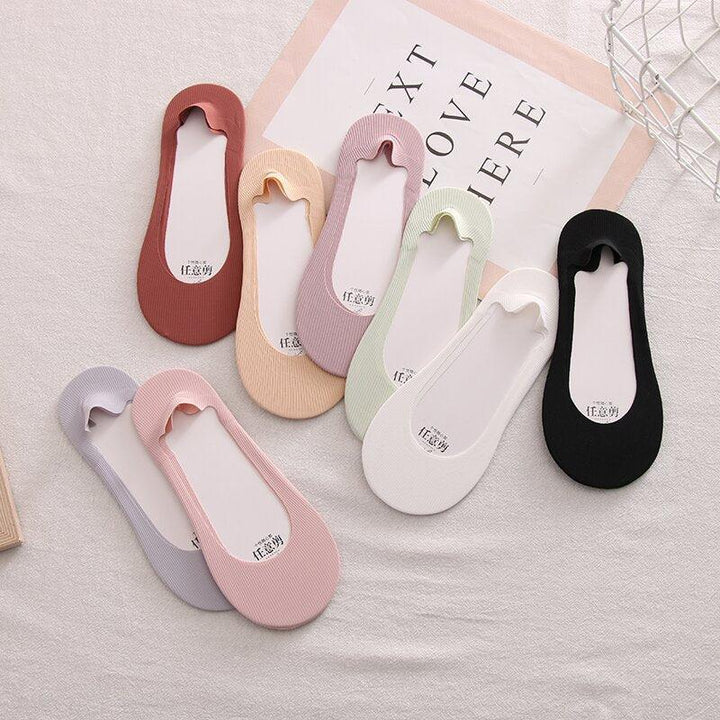 Set of eight colorful no-show liner socks in pastel and neutral tones arranged on fabric with text background