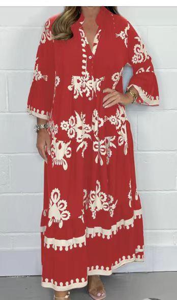 Woman wearing a red maxi dress with white floral patterns and 3/4 sleeves in front of a white brick wall