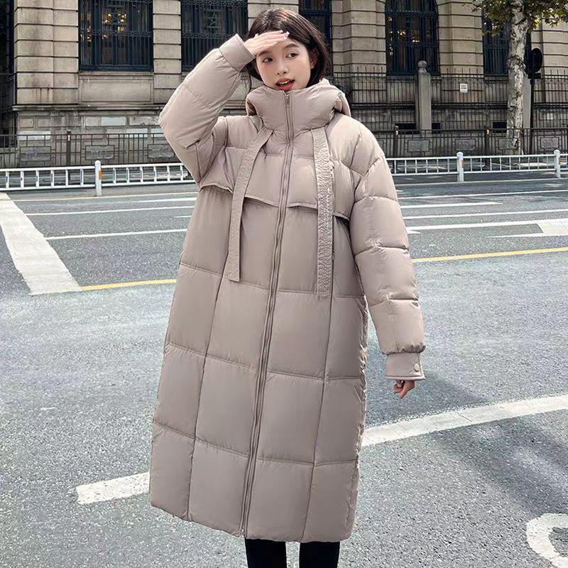 Woman wearing long beige padded winter coat with high collar on city street
