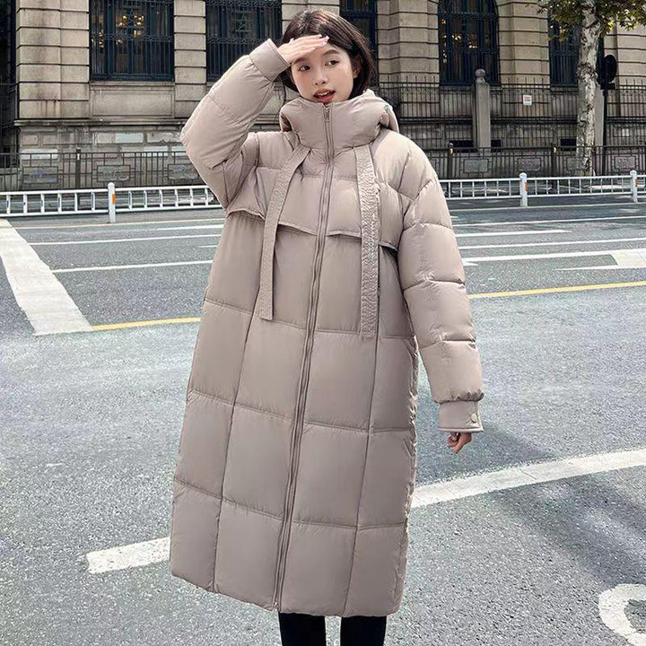 Woman wearing long beige padded winter coat with high collar on city street