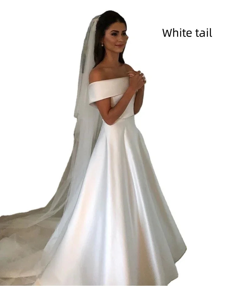 Bride in elegant off-shoulder white satin wedding dress with long trailing veil