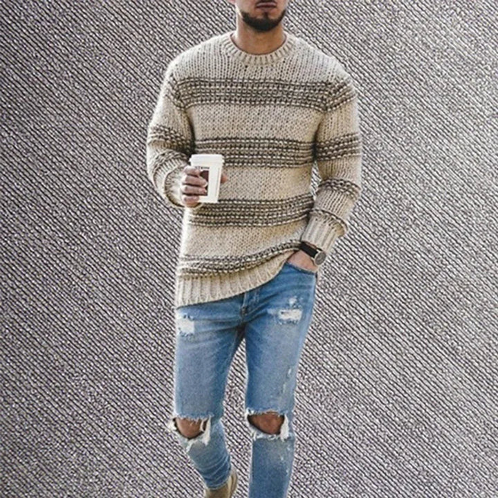 Man wearing beige striped knit sweater and ripped blue jeans holding a coffee cup