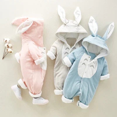 Three soft baby jumpsuits with bunny ears in pink, gray, and blue colors on a light background