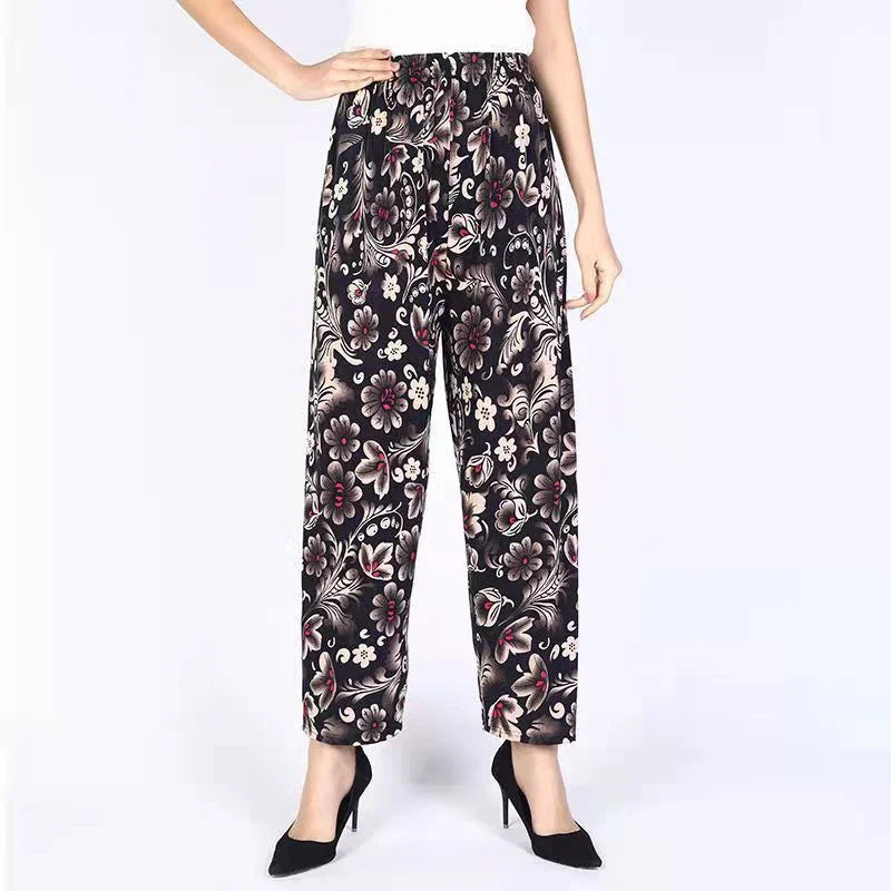 Woman wearing black floral pattern wide-leg pants and black high heels on white background