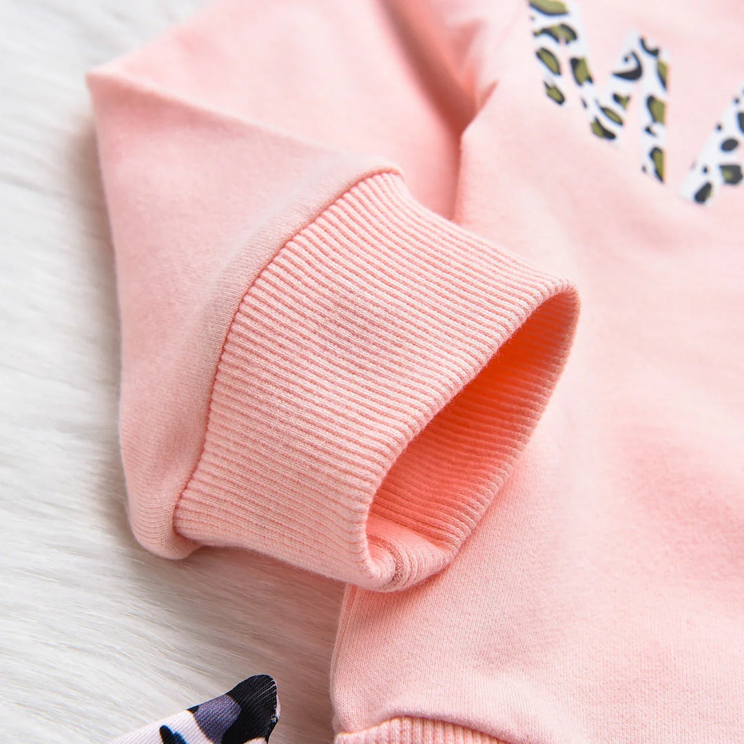 Close-up of a pink sweatshirt sleeve with ribbed cuff and leopard print detail on fabric