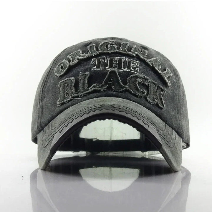 Faded black distressed baseball cap with embroidered text 'ORIGINAL THE BLACK' on front