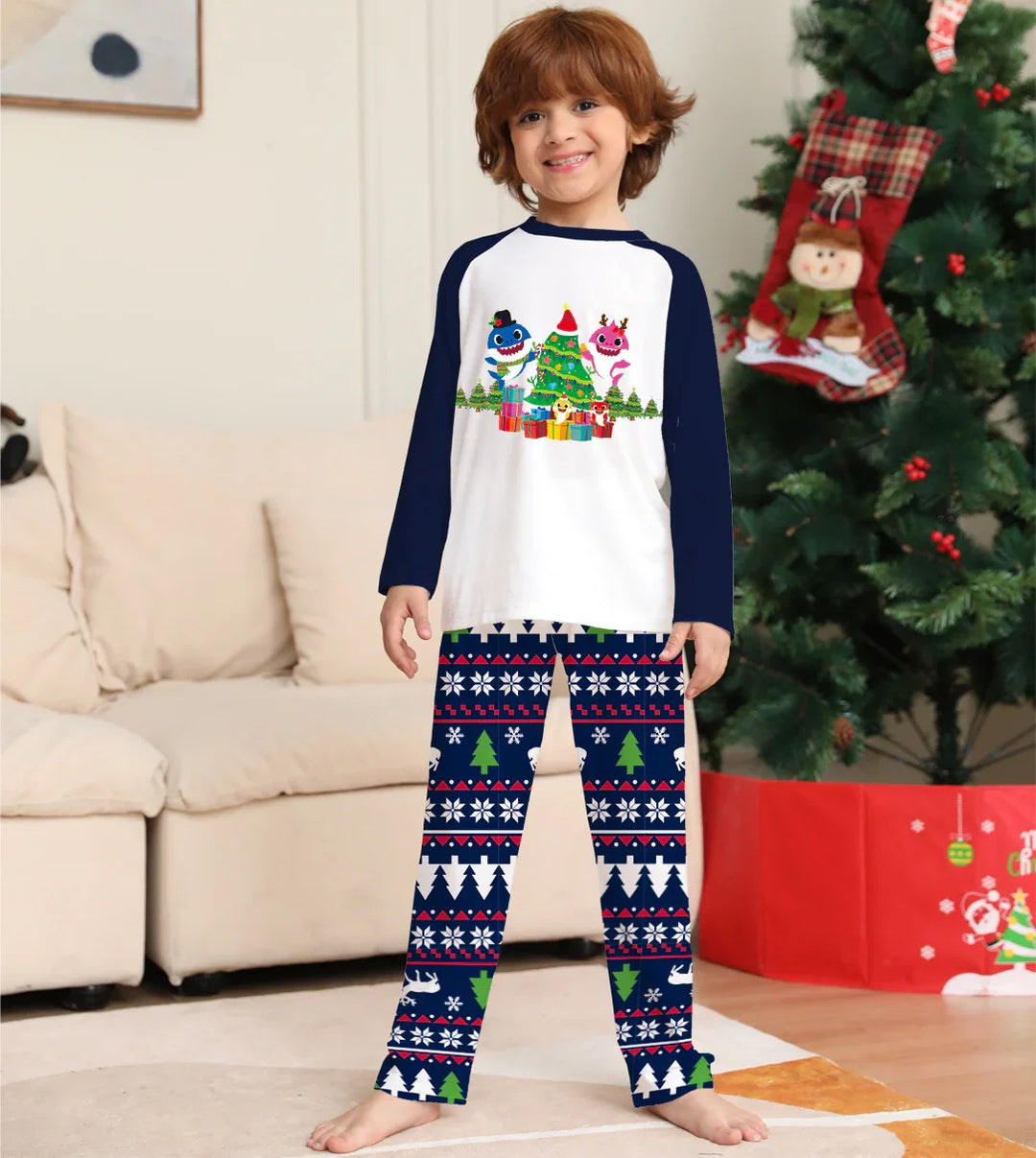 Smiling child in Christmas pajamas with animated characters, standing by decorated Christmas tree