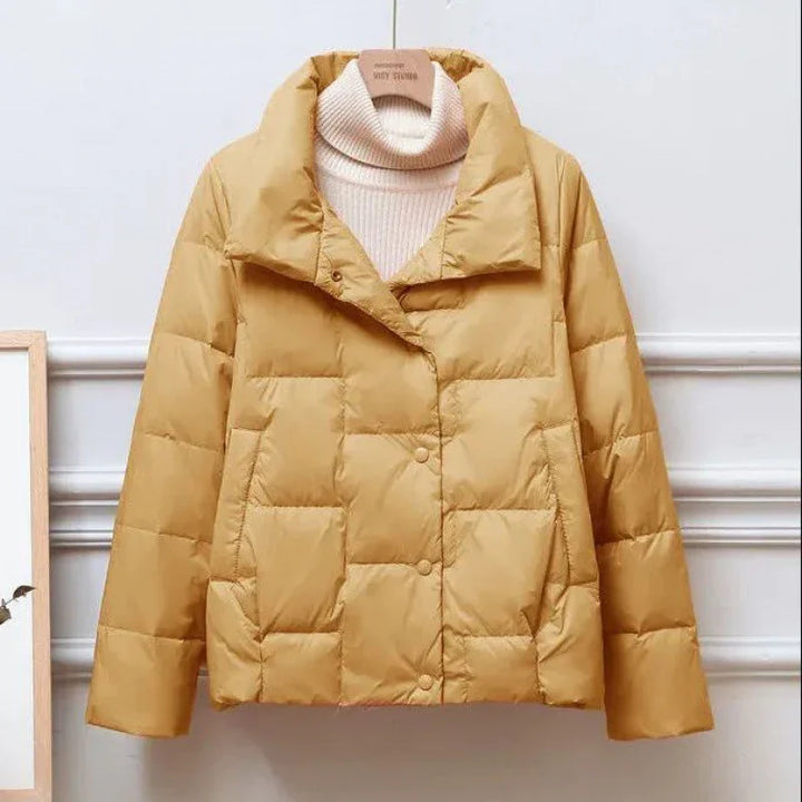 Women's mustard yellow quilted puffer jacket with high collar over beige turtleneck sweater