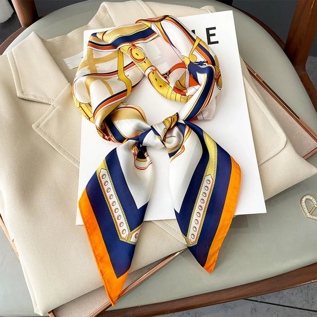 Silk scarf with orange, navy, and gold chain print on beige blazer and magazine on glass table