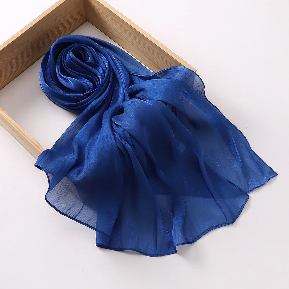 Elegant sheer blue silk scarf displayed in a wooden frame on white background
