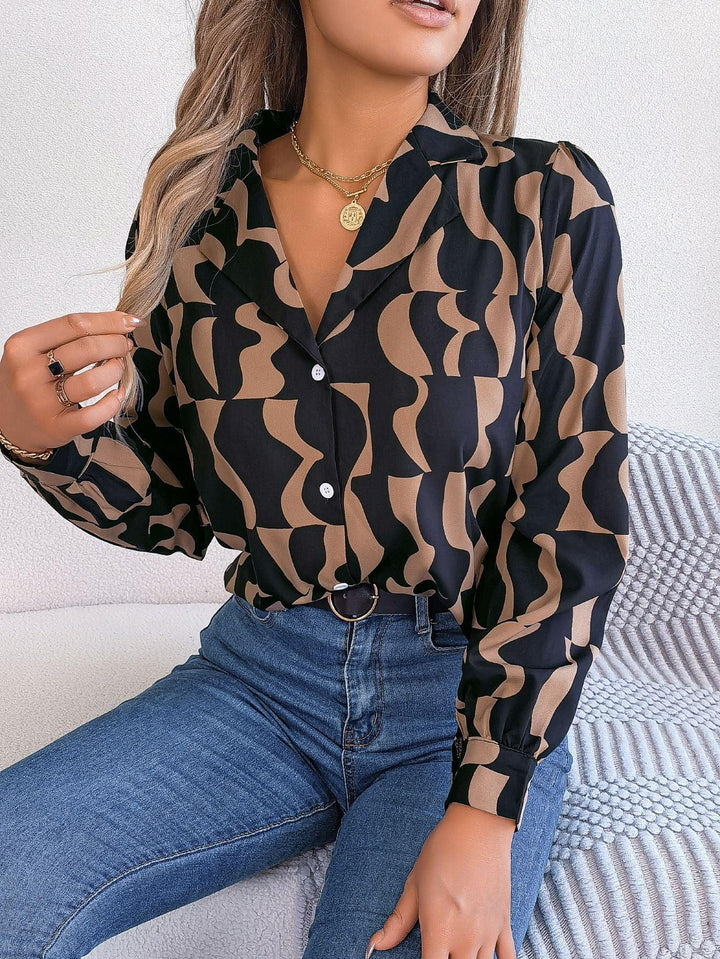 Woman wearing black and brown geometric pattern blouse with puff sleeves and blue jeans sitting indoors