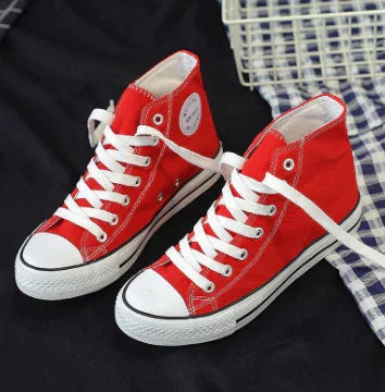Pair of classic red high-top canvas sneakers with white laces and rubber soles on dark fabric