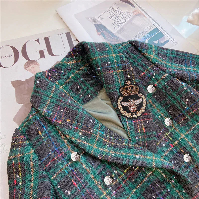 Green and black plaid blazer with silver buttons and embroidered bee crest on lapel, laid on Vogue magazine