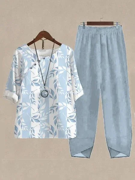 Light blue leaf print blouse with 3/4 sleeves paired with loose light blue pants on hangers