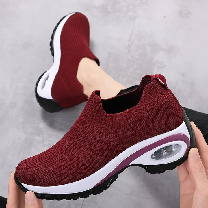 Maroon slip-on knit sneakers with white and black sole, cushioned air bubble heel, worn on feet
