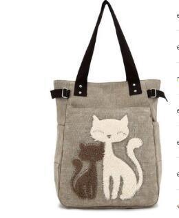 Beige tote bag with black handles featuring embroidered white and brown cats design