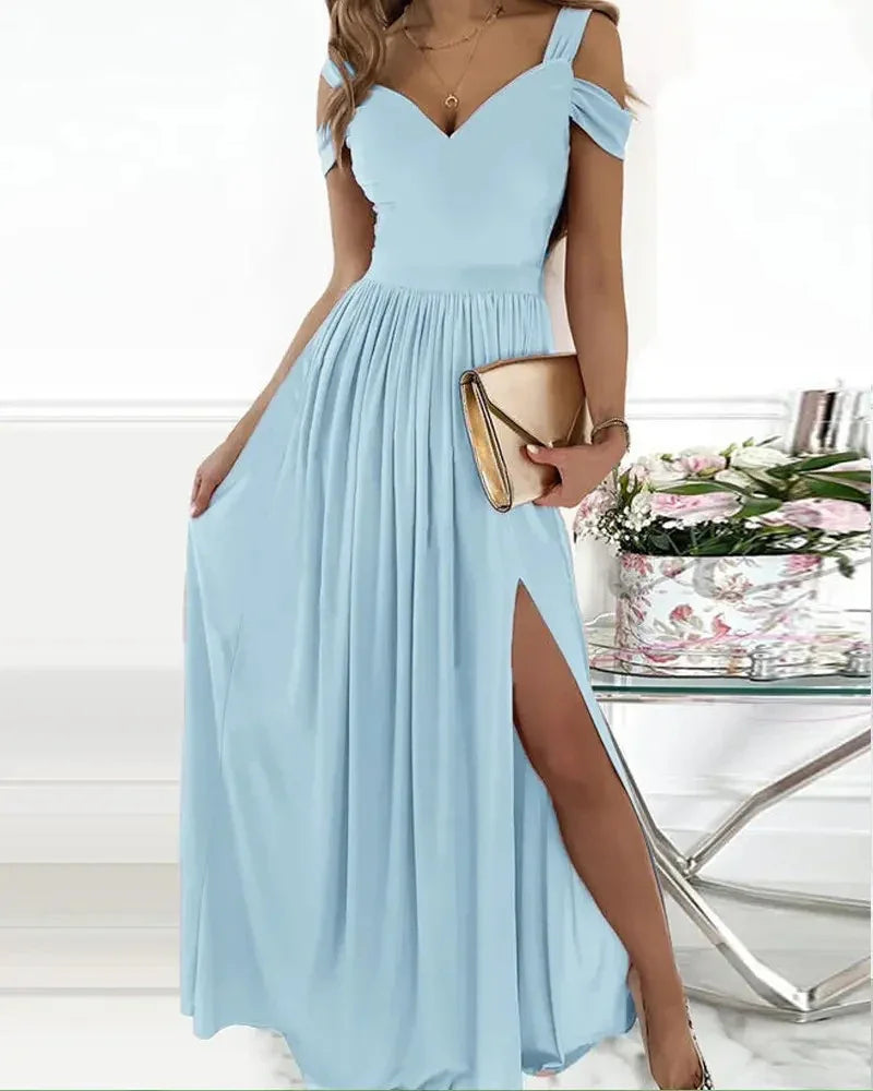 Woman in light blue off-shoulder maxi dress with thigh slit holding a gold clutch handbag