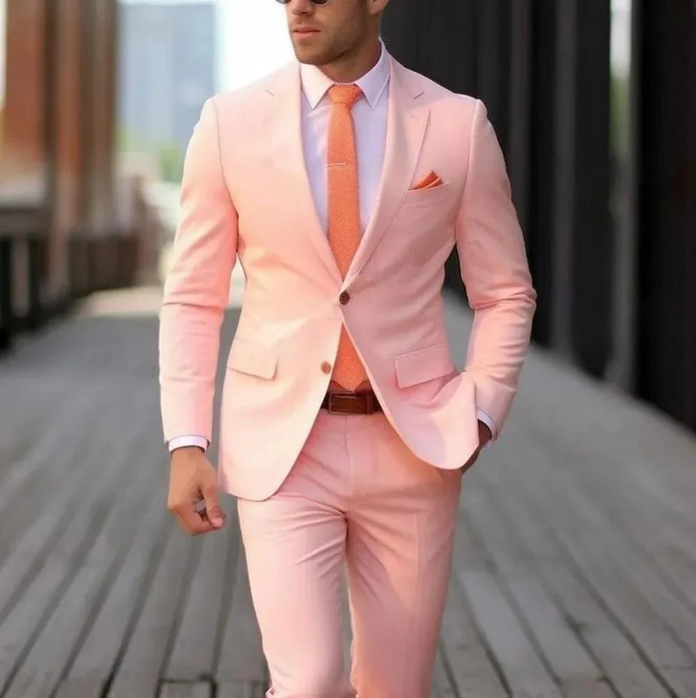 Man wearing a light pink suit with orange tie and pocket square walking on wooden boardwalk