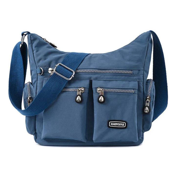 Blue canvas crossbody bag with multiple zippered pockets and adjustable strap