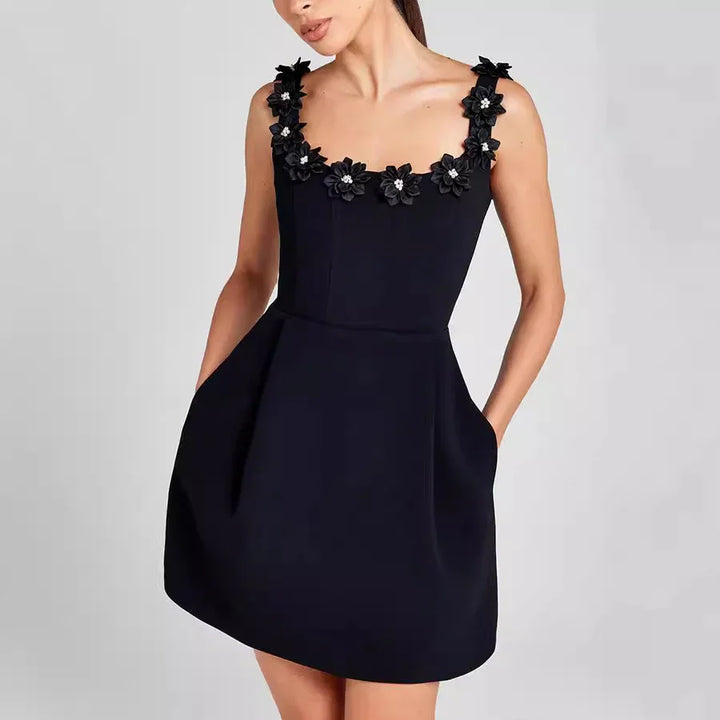 Woman wearing a sleeveless black mini dress with floral embellished straps and pockets