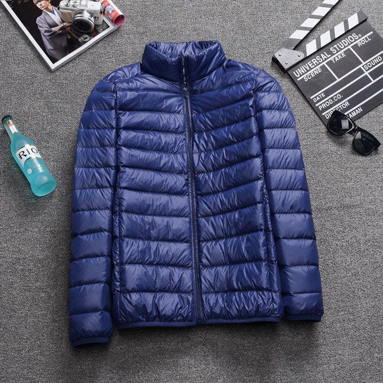 Blue lightweight quilted puffer jacket with zipper on gray carpet, surrounded by film clapper, sunglasses, magazine, and blue bottle