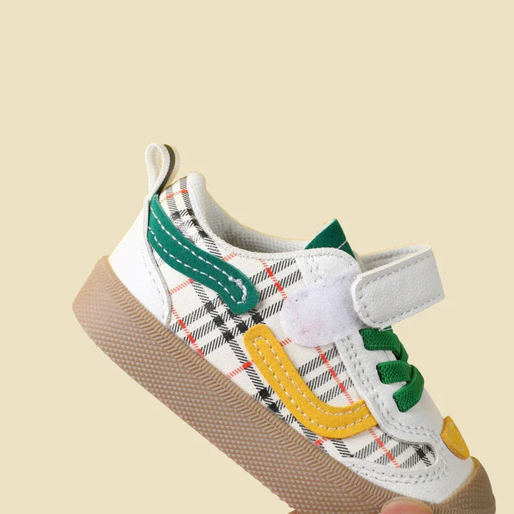 Toddler sneaker with plaid pattern, green and yellow accents, white strap, and brown sole