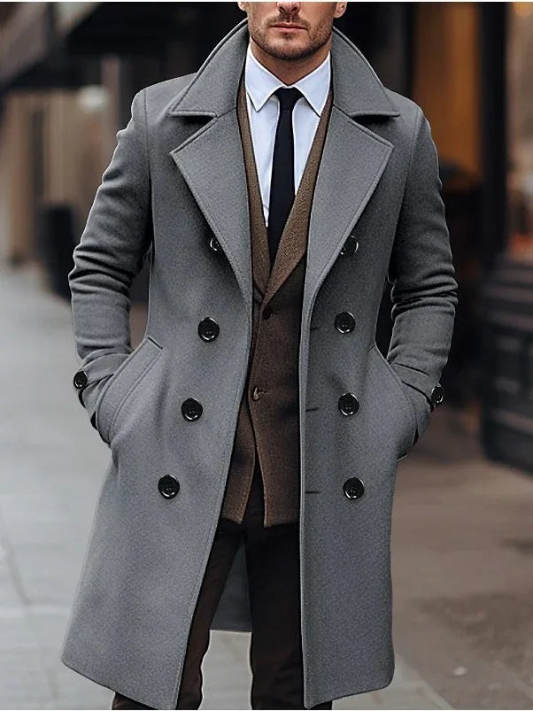 Man wearing stylish grey double-breasted wool coat over brown suit and black tie in urban setting