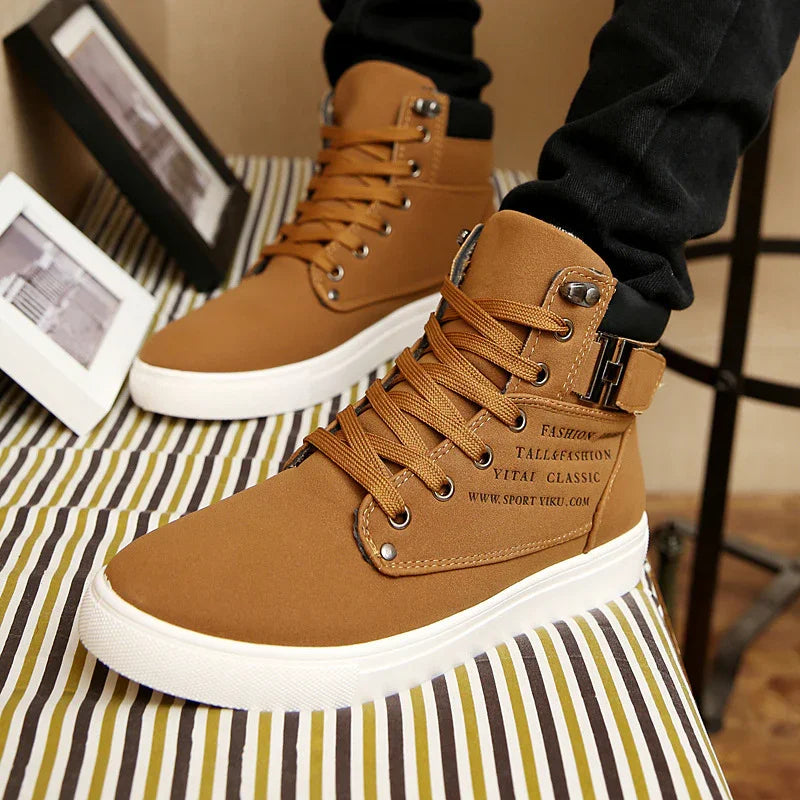 brown high-top casual sneakers with white soles and black printed text on side worn with black pants