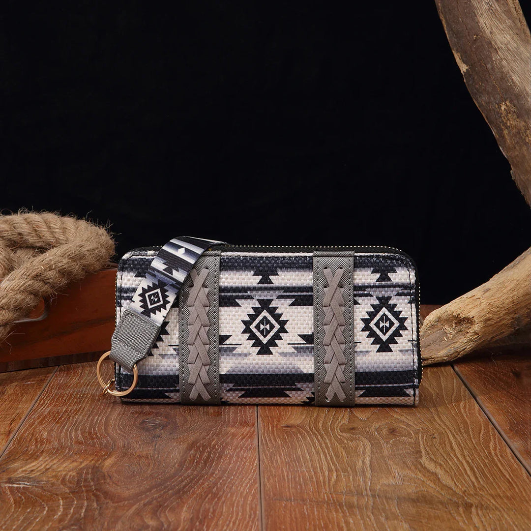 Black and white tribal-patterned zip wallet with braided leather accents and wrist strap on wood floor
