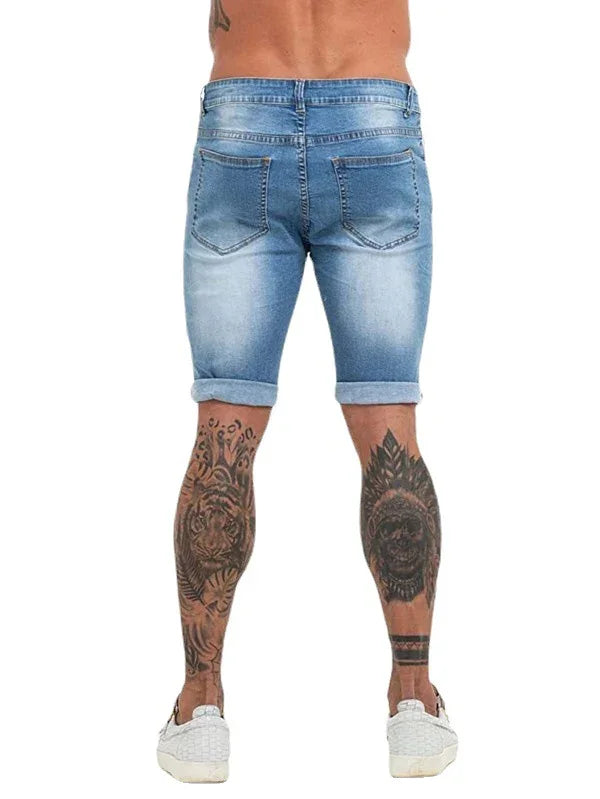 Back view of man wearing light blue rolled-up denim shorts with leopard and skull leg tattoos