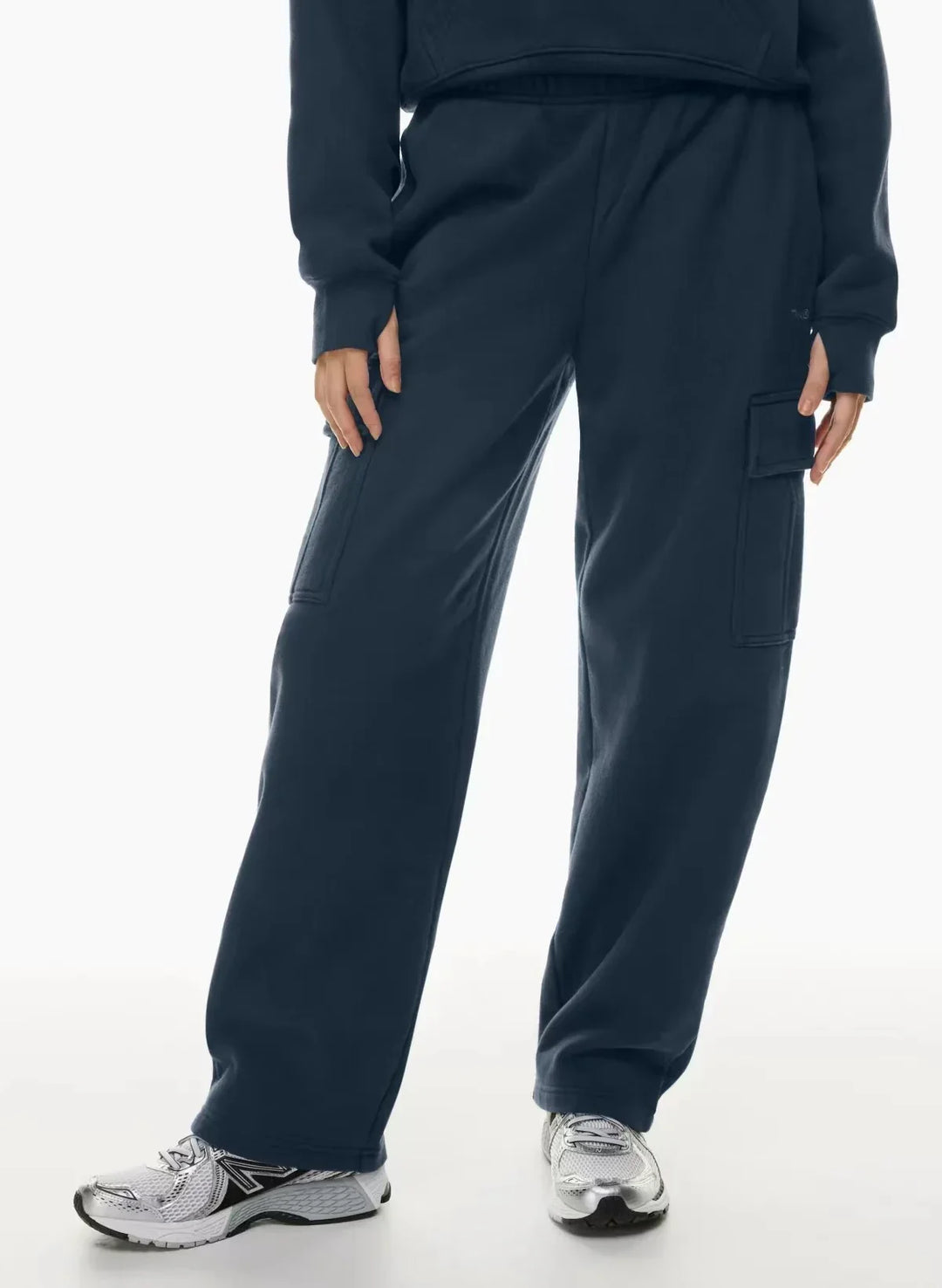 Woman wearing navy blue cargo sweatpants and gray sneakers on white background