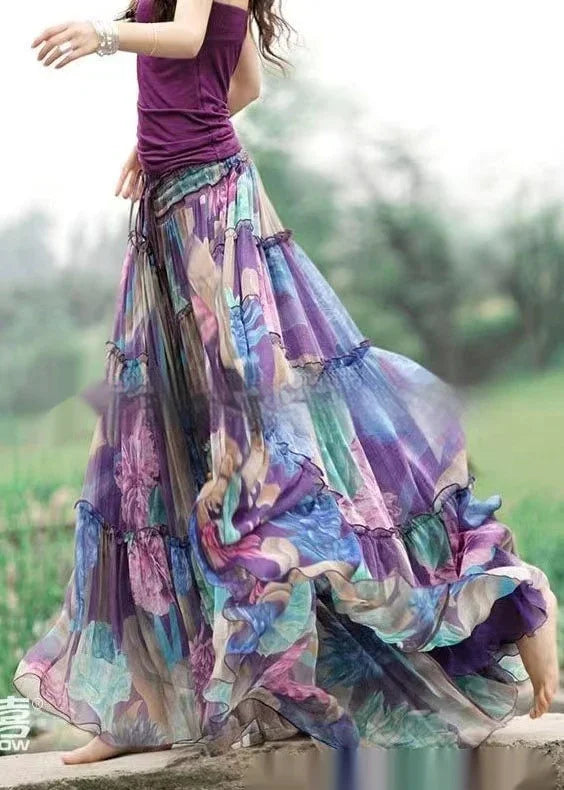Woman wearing a flowing, colorful, floral maxi skirt and purple sleeveless top outdoors barefoot