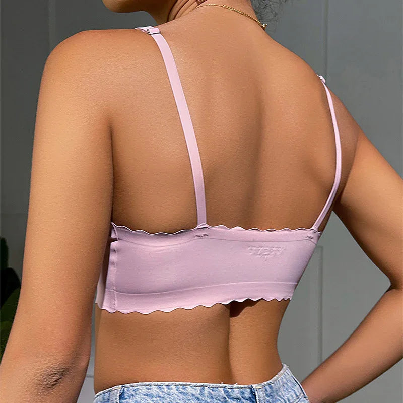 Back view of woman wearing light pink scalloped-edge crop top with spaghetti straps and blue jeans