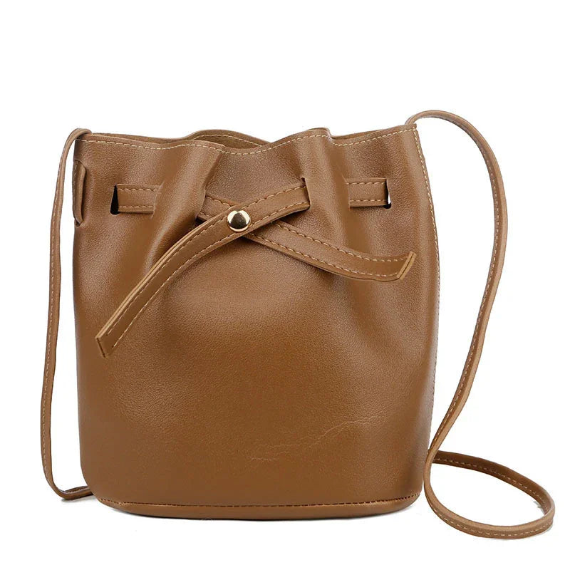 Brown leather bucket bag with adjustable strap and drawstring closure on white background
