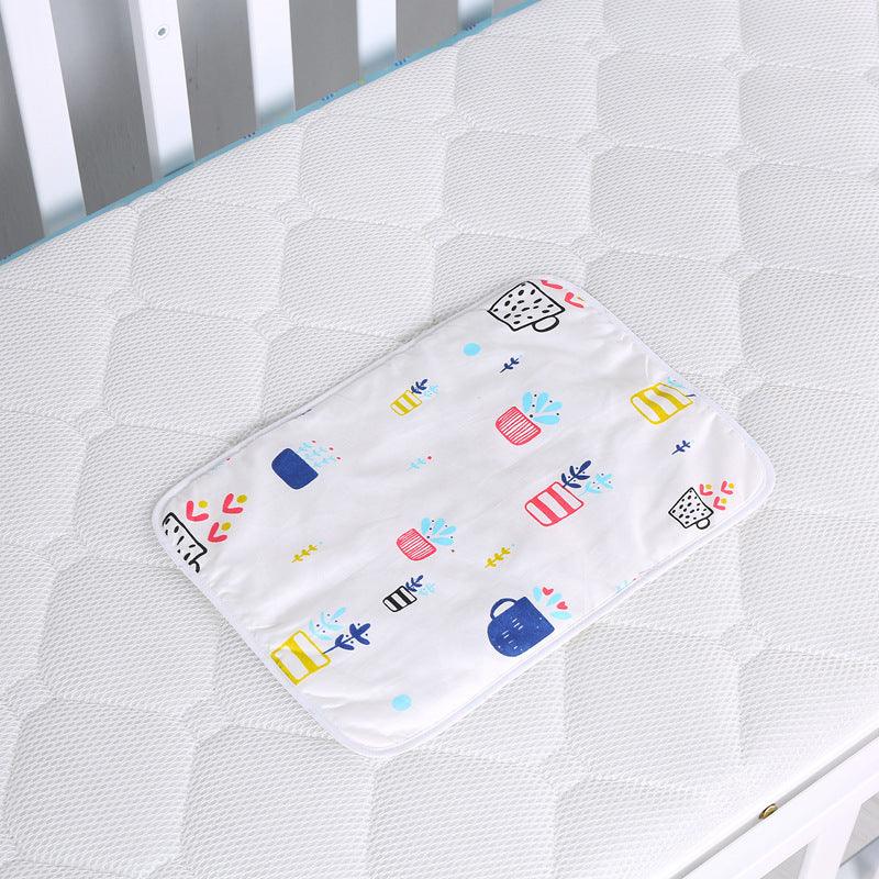 White baby changing pad with colorful potted plant patterns on a white quilted crib mattress
