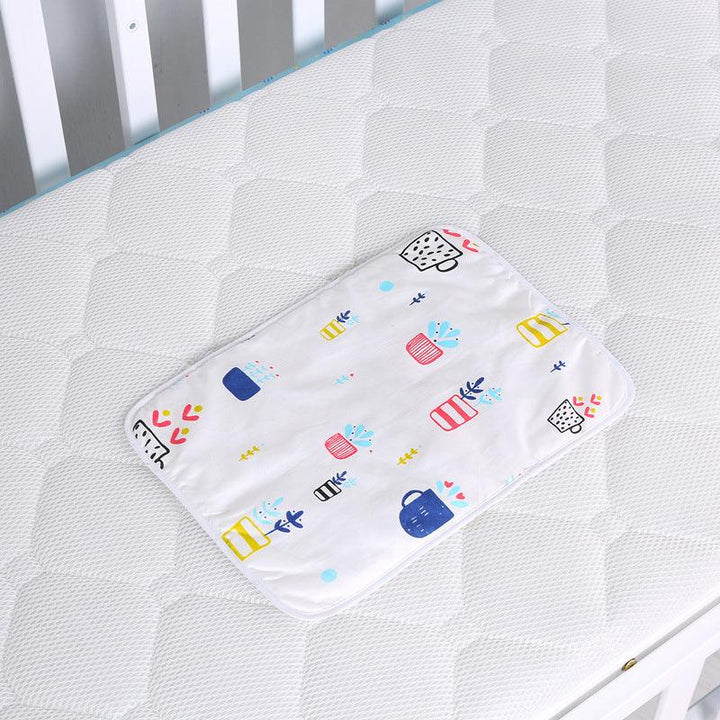 White baby changing pad with colorful potted plant patterns on a white quilted crib mattress
