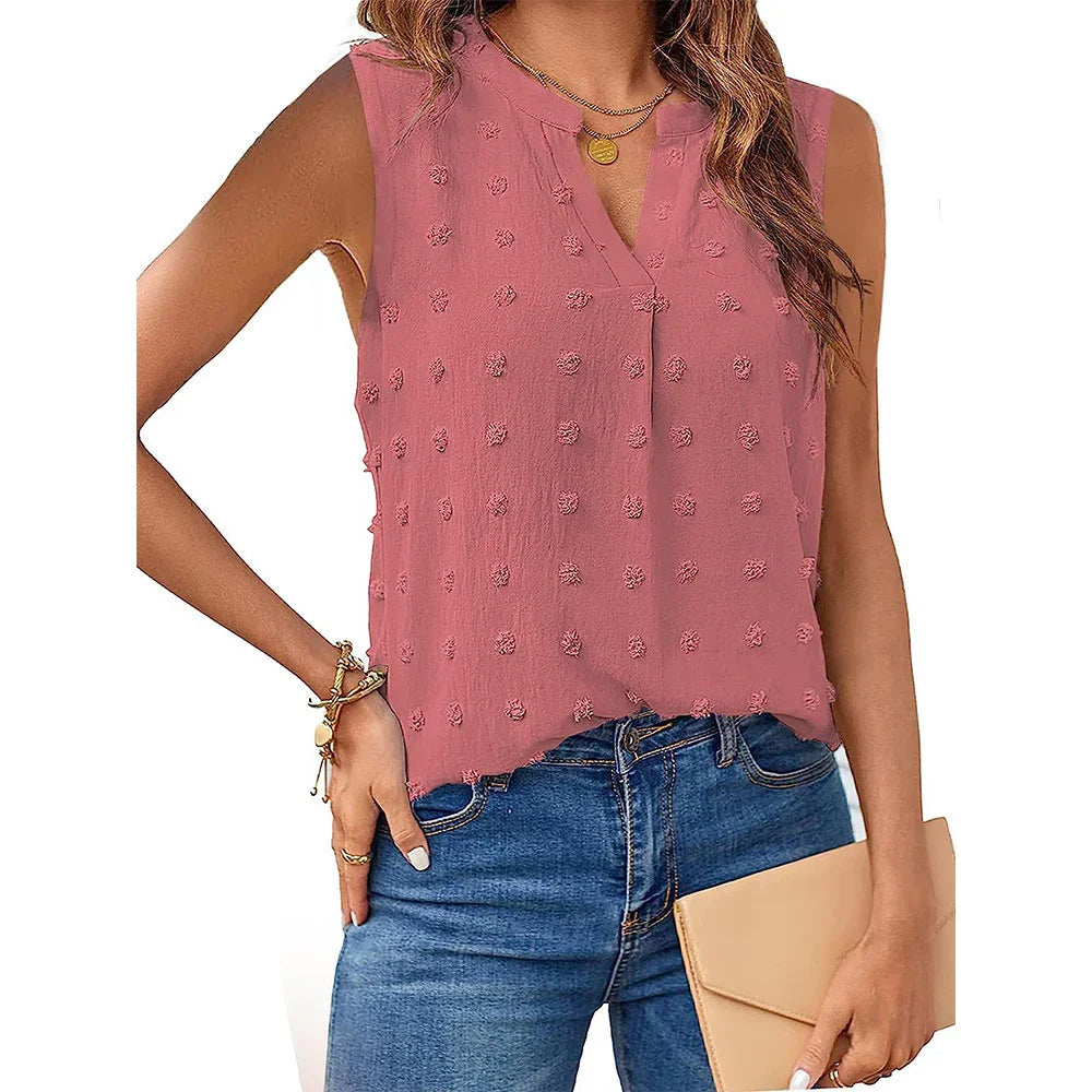 Woman wearing sleeveless pink textured blouse with blue jeans holding beige clutch
