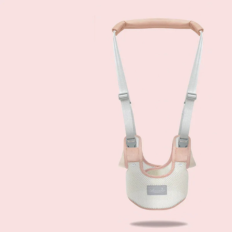 Light pink and beige baby safety walking harness with adjustable straps on a pale pink background