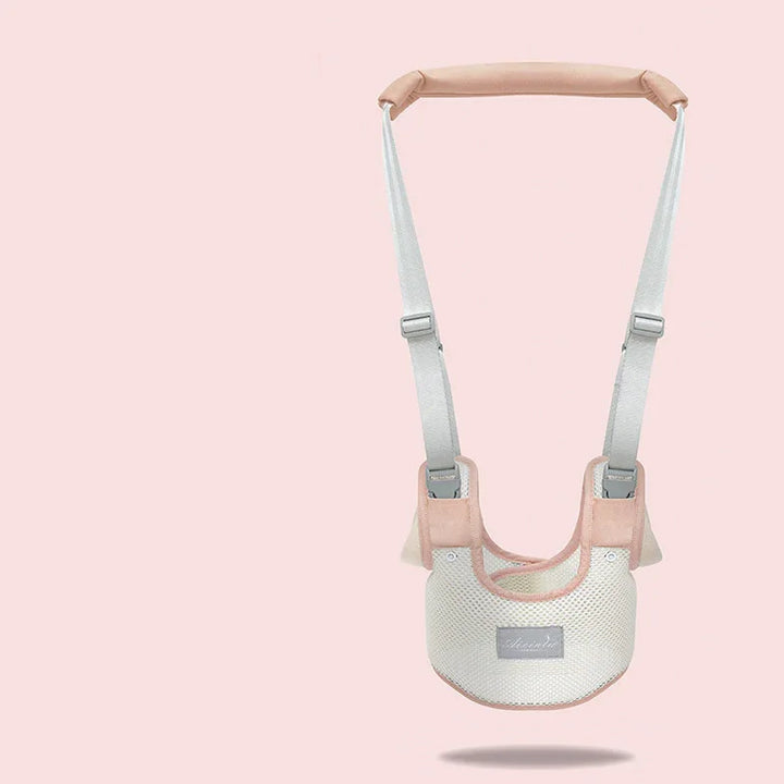 Light pink and beige baby safety walking harness with adjustable straps on a pale pink background
