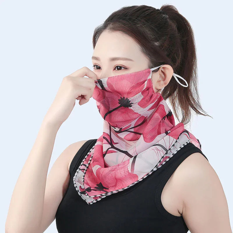 Woman wearing a pink floral patterned face mask scarf with ear loops and black sleeveless top