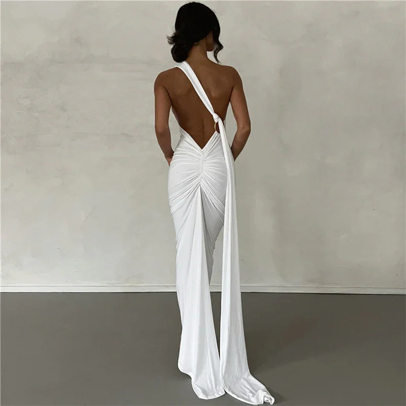 Woman wearing elegant white backless ruched gown with long draped sash in minimal studio