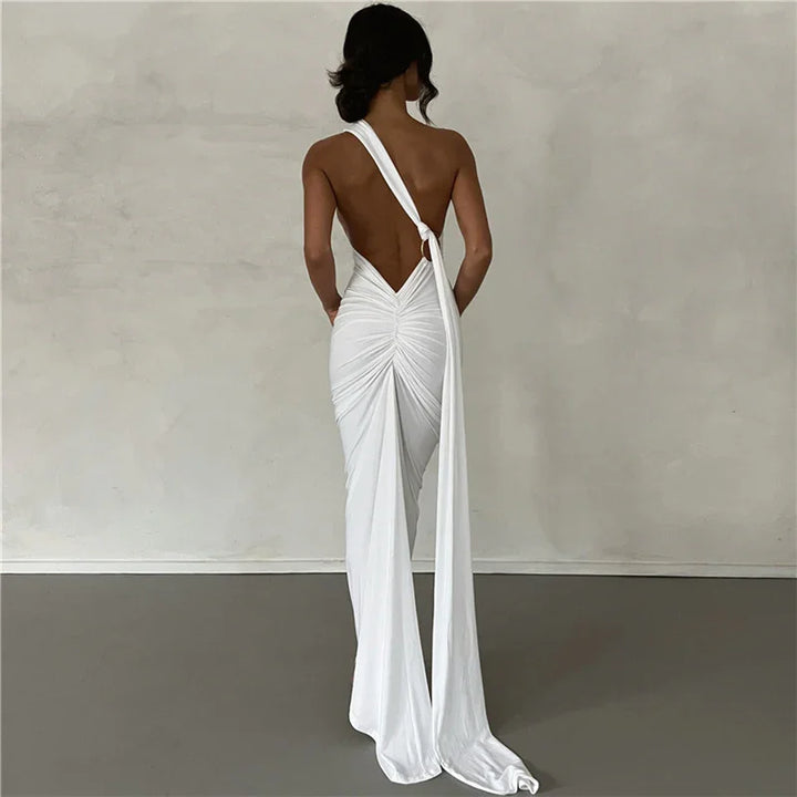 Woman wearing elegant white backless ruched gown with long draped sash in minimal studio