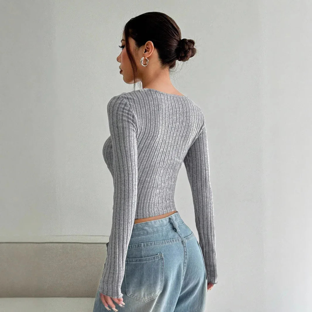 Woman with braided bun wearing a fitted gray ribbed long-sleeve top and blue jeans