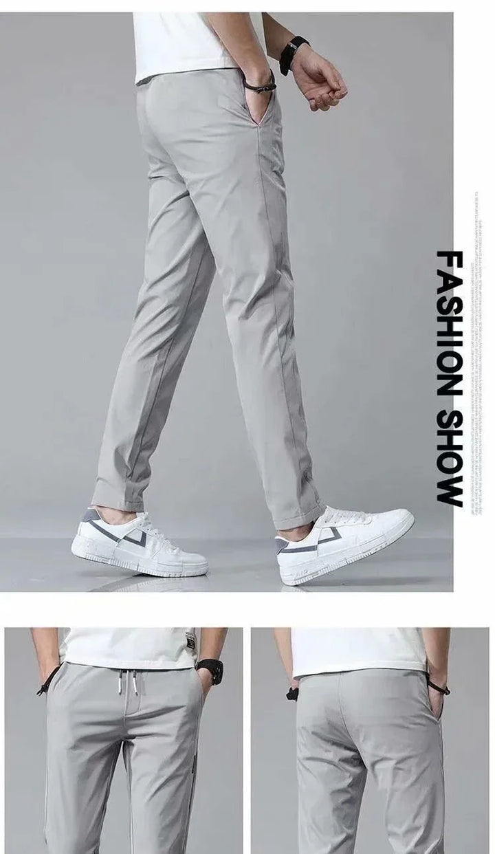 Men's light gray casual pants paired with white sneakers in a fashion show setting