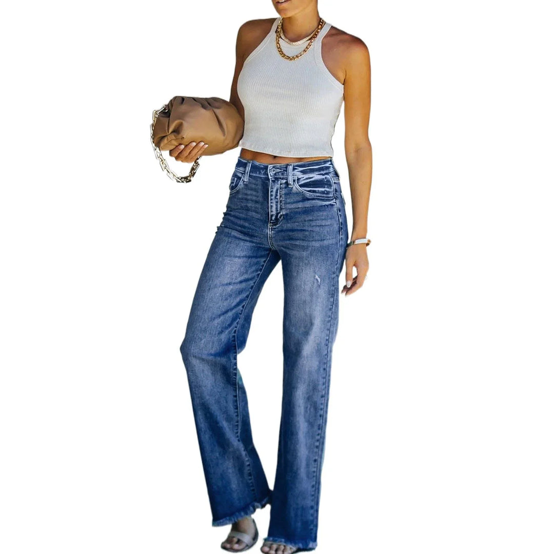 Woman wearing white sleeveless crop top, high-waisted wide-leg blue jeans, holding brown clutch bag